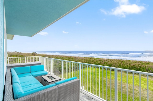 balcony featuring an outdoor living space with a fire pit, a water view, and a beach view