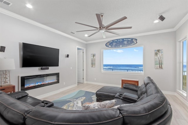 living room featuring crown molding, light wood-type flooring, visible vents, and a glass covered fireplace