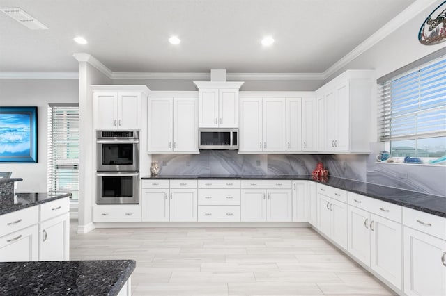 kitchen featuring visible vents, white cabinets, appliances with stainless steel finishes, decorative backsplash, and dark stone countertops