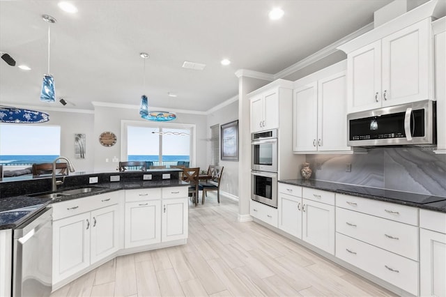 kitchen with ornamental molding, decorative light fixtures, stainless steel appliances, light wood-style floors, and a sink