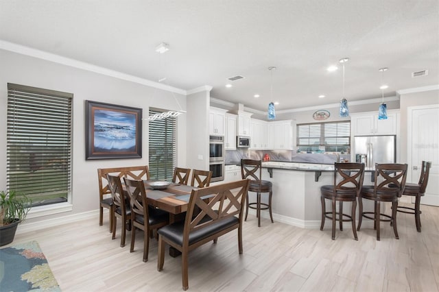 dining area featuring baseboards, light wood-type flooring, visible vents, and crown molding