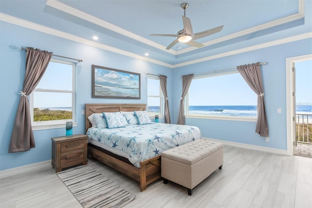 bedroom with ornamental molding, a water view, a raised ceiling, and baseboards