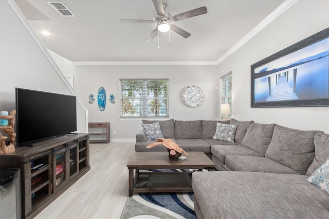 living room with light wood finished floors, visible vents, ornamental molding, a ceiling fan, and baseboards