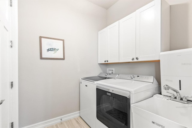 washroom featuring cabinet space, baseboards, independent washer and dryer, light wood-style floors, and a sink