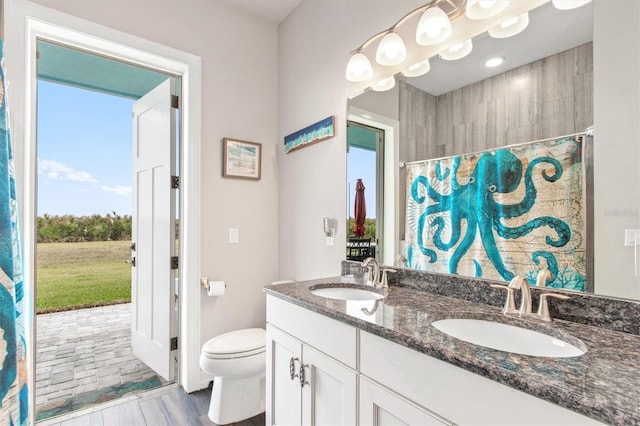 bathroom with double vanity, a shower with shower curtain, a sink, and toilet