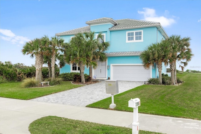 view of front of home with an attached garage, decorative driveway, and a front yard