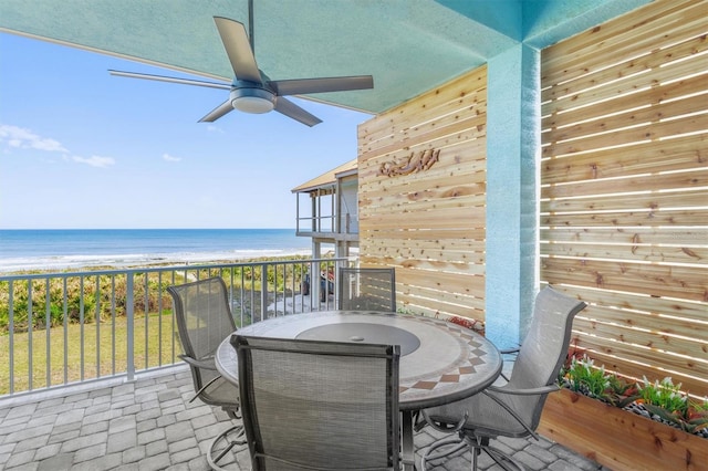 exterior space with a water view, ceiling fan, outdoor dining area, and a view of the beach