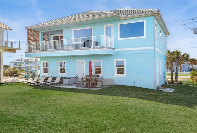 rear view of house with a lawn, a patio area, and stucco siding