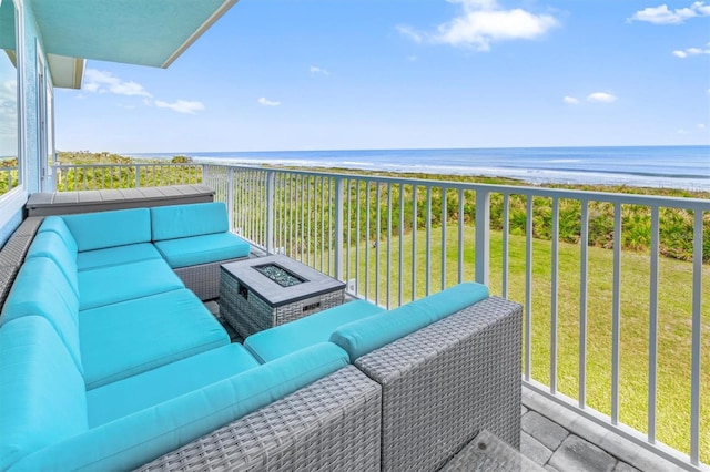 balcony featuring a water view, a beach view, and an outdoor living space with a fire pit