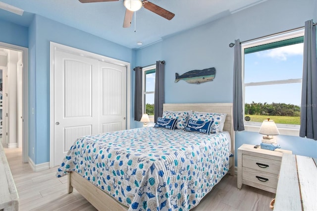 bedroom featuring light wood-type flooring, multiple windows, and a closet