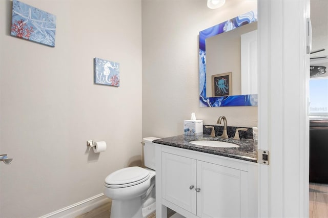 bathroom with toilet, baseboards, wood finished floors, and vanity