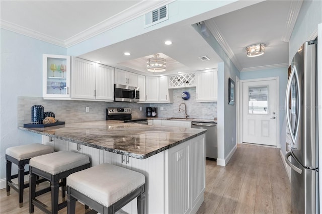 kitchen with white cabinetry, kitchen peninsula, a kitchen bar, and stainless steel appliances