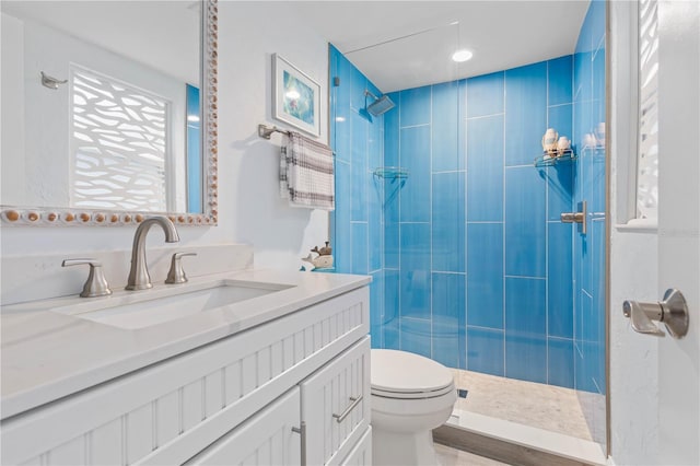 bathroom with a tile shower, vanity, and toilet