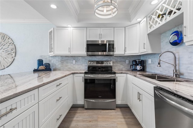 kitchen featuring stainless steel appliances, sink, a raised ceiling, white cabinets, and light wood-type flooring