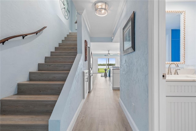 staircase featuring sink, hardwood / wood-style floors, ceiling fan, and crown molding