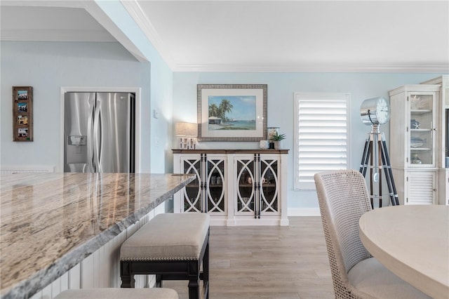 dining room with light hardwood / wood-style flooring and crown molding