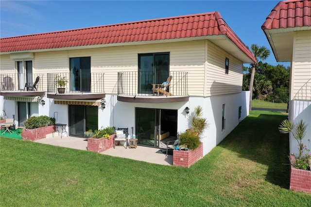 rear view of house featuring a balcony, a lawn, and a patio area