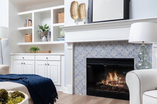 bedroom featuring a tiled fireplace and light hardwood / wood-style flooring