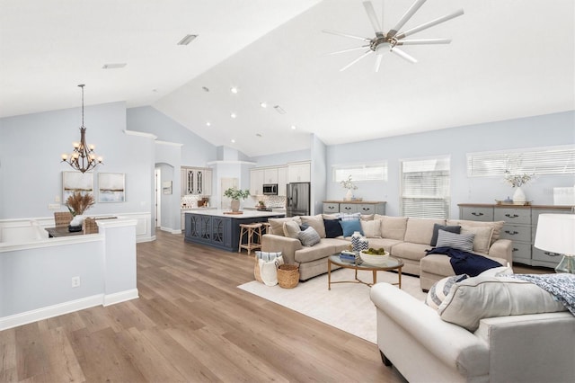 living room featuring high vaulted ceiling, light hardwood / wood-style floors, and ceiling fan with notable chandelier