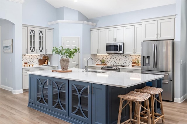 kitchen featuring light hardwood / wood-style flooring, white cabinetry, appliances with stainless steel finishes, and a kitchen island with sink