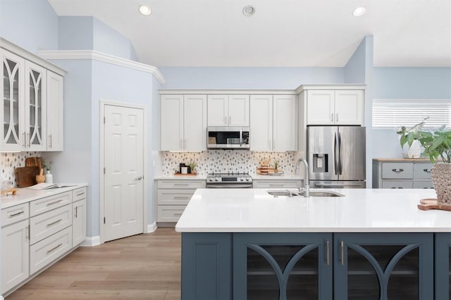 kitchen with stainless steel appliances, white cabinetry, sink, tasteful backsplash, and light wood-type flooring