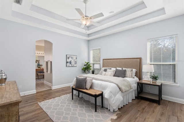 bedroom featuring hardwood / wood-style flooring, ceiling fan, and a raised ceiling