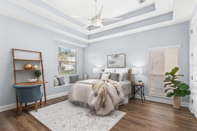 bedroom featuring dark wood-type flooring, ceiling fan, and a raised ceiling