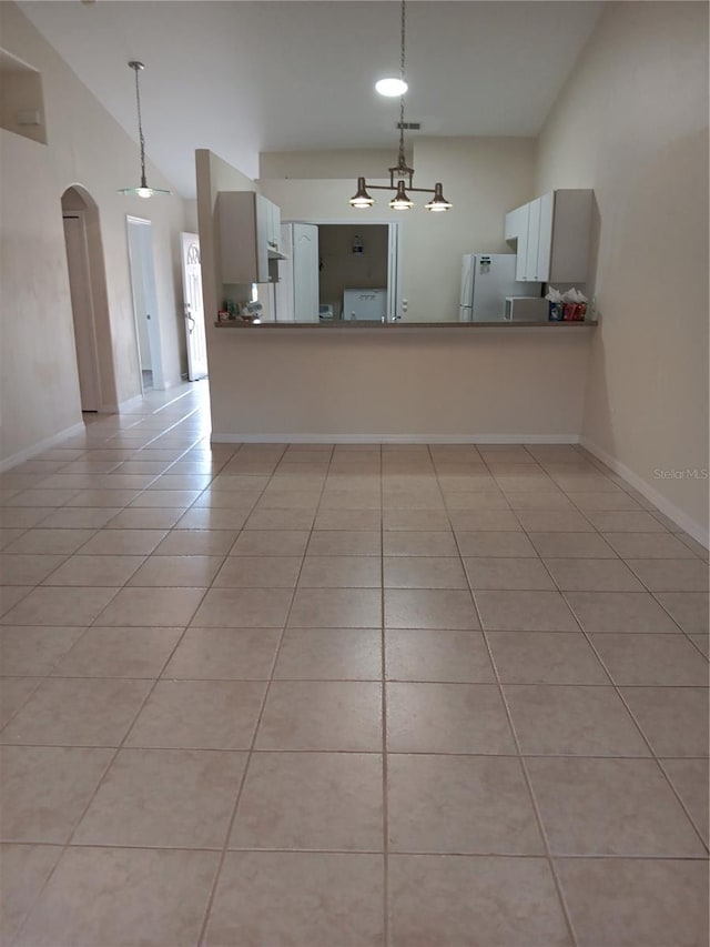 tiled empty room featuring a notable chandelier