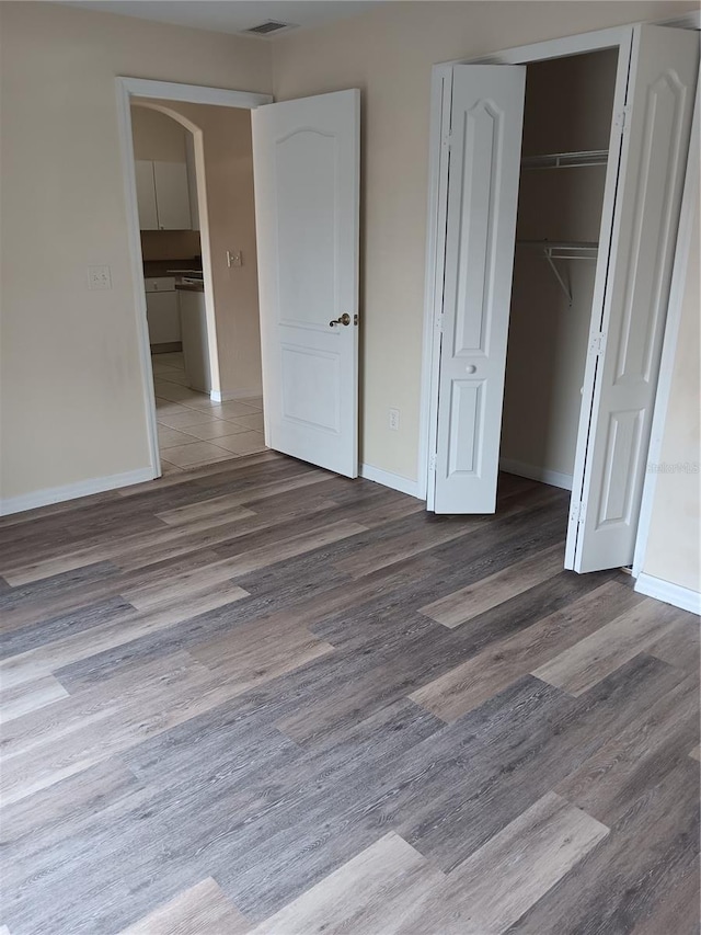 unfurnished bedroom with hardwood / wood-style flooring and a closet