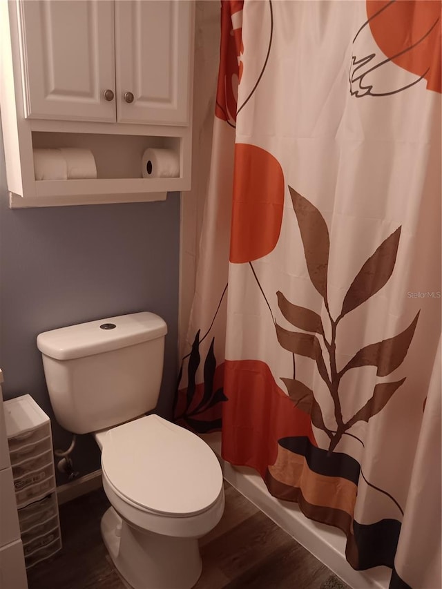 bathroom with curtained shower, wood-type flooring, and toilet