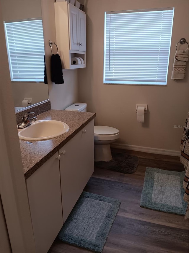 bathroom with hardwood / wood-style flooring, toilet, and vanity