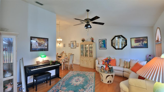 living room featuring hardwood / wood-style floors, ceiling fan with notable chandelier, and lofted ceiling