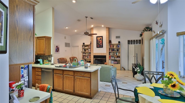 kitchen with light tile patterned floors, a large fireplace, stainless steel dishwasher, and ceiling fan