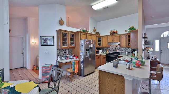 kitchen featuring kitchen peninsula, decorative backsplash, a kitchen bar, stainless steel appliances, and light tile patterned flooring