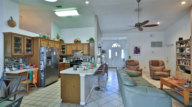 kitchen featuring backsplash, a breakfast bar, stainless steel appliances, light tile patterned floors, and decorative light fixtures