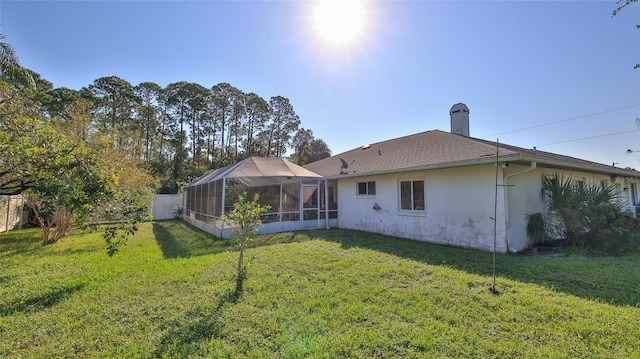 rear view of property featuring glass enclosure and a yard