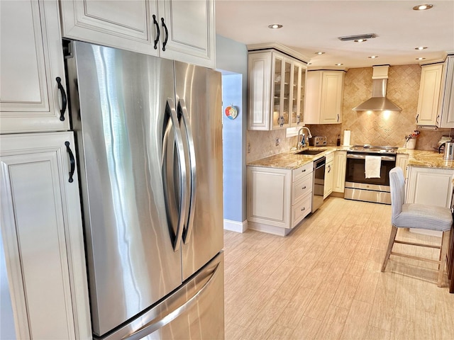 kitchen featuring light stone counters, sink, wall chimney exhaust hood, and stainless steel appliances