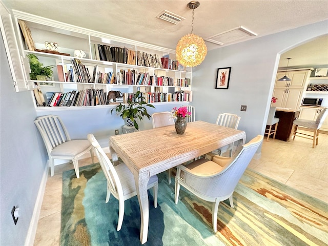 tiled dining area with a textured ceiling and a notable chandelier