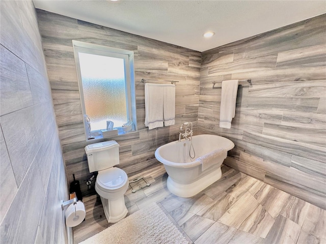 bathroom with a bathtub, tile walls, and toilet