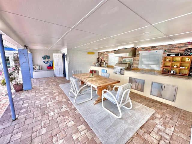 dining space with a paneled ceiling and brick wall