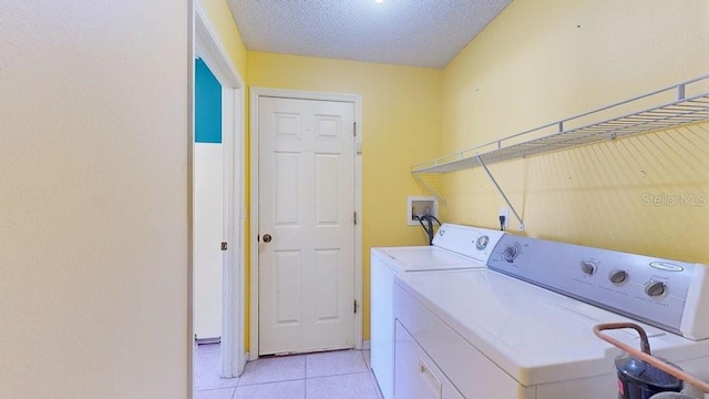 laundry room with a textured ceiling, separate washer and dryer, and light tile patterned flooring