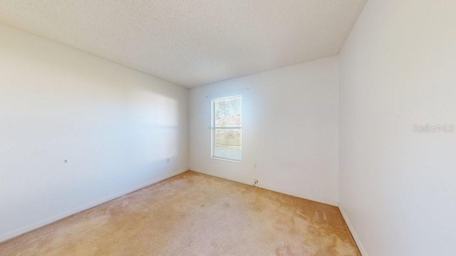 unfurnished room with a textured ceiling and light colored carpet