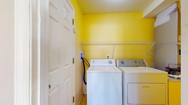 laundry area with separate washer and dryer and a textured ceiling