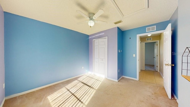 unfurnished bedroom featuring light carpet, a textured ceiling, a closet, and ceiling fan