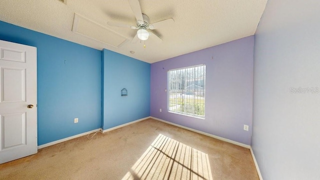 spare room featuring ceiling fan, light colored carpet, and a textured ceiling