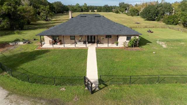 back of property with a patio, a lawn, and a rural view