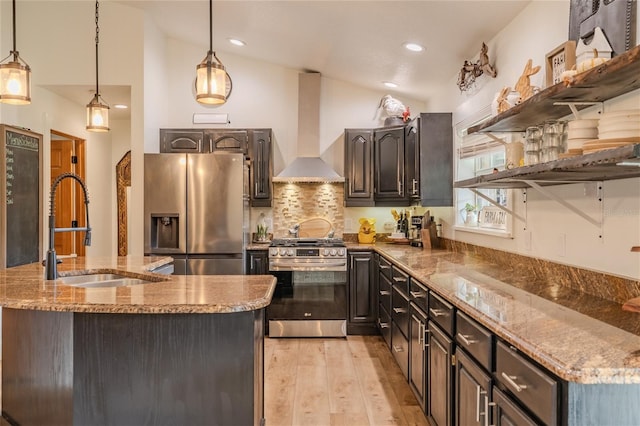 kitchen with pendant lighting, wall chimney range hood, appliances with stainless steel finishes, and lofted ceiling