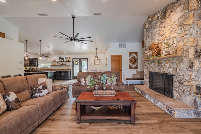 living room with light hardwood / wood-style floors, sink, ceiling fan, a fireplace, and lofted ceiling