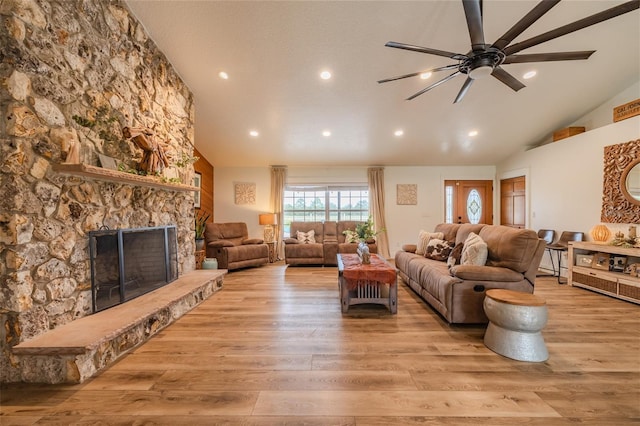 living room with a fireplace, light hardwood / wood-style flooring, ceiling fan, and high vaulted ceiling