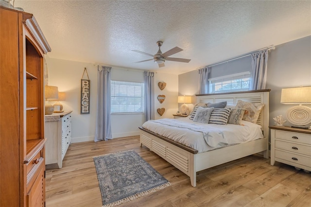 bedroom featuring a textured ceiling, light hardwood / wood-style flooring, multiple windows, and ceiling fan